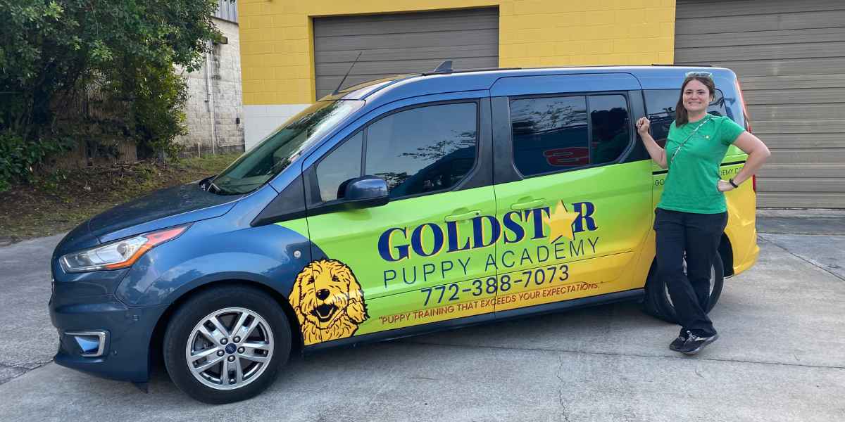 Gerry-Anna of Goldstar Puppy Academy standing next to the branded dog daycare van in Vero Beach